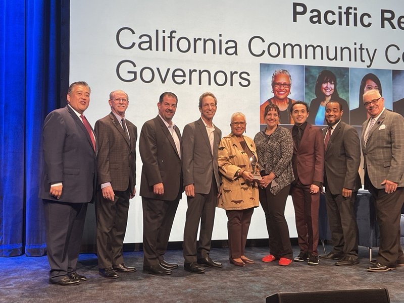 Photo of nine Board of Governors members on stage facing the audience, in front of a screen "Pacific Region California Community Governors"