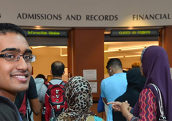 School campus with sign Admissions and Records Financial with students waiting in line and one male appearing student facing camera