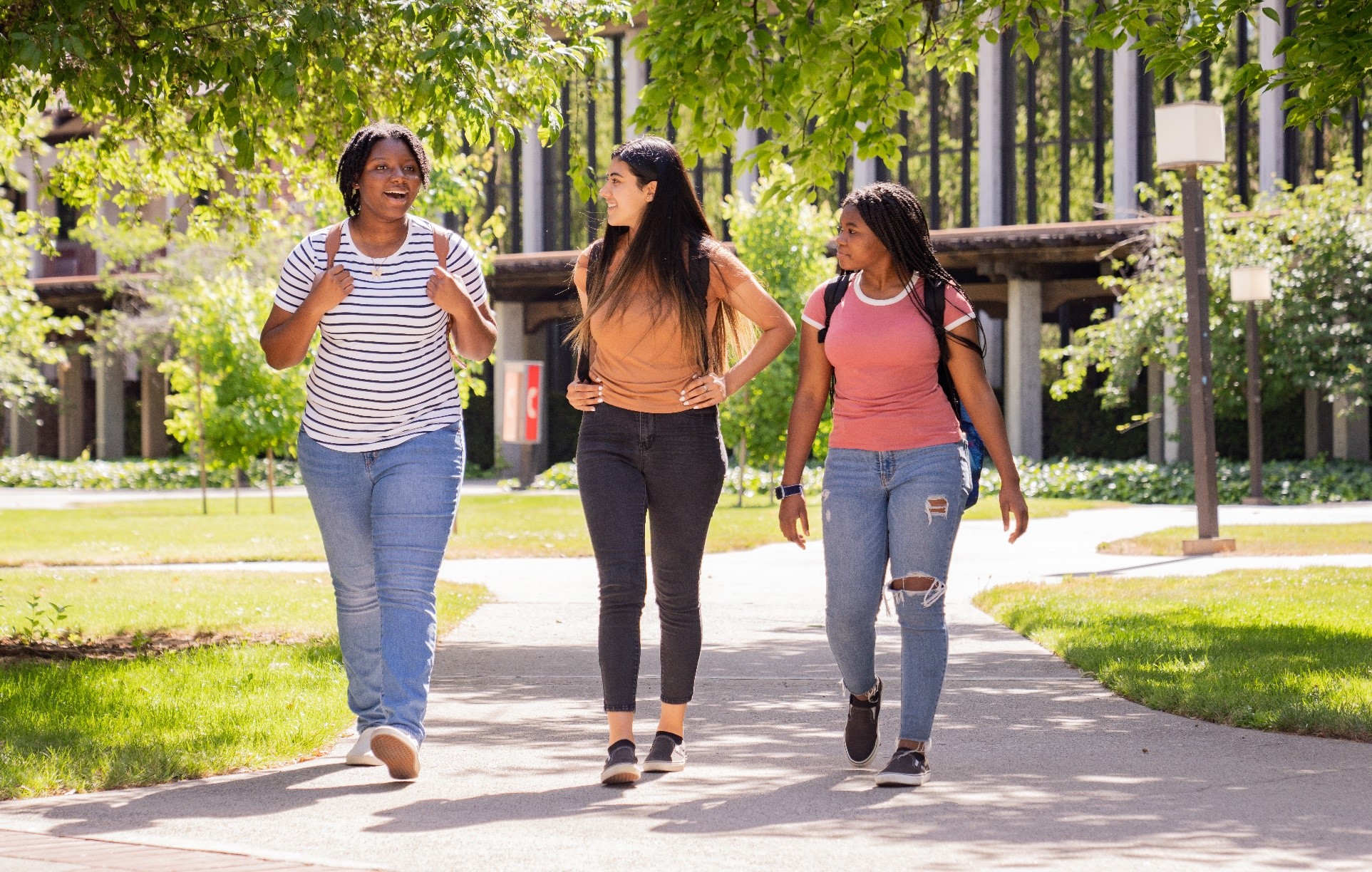 three students walking outside on a path 