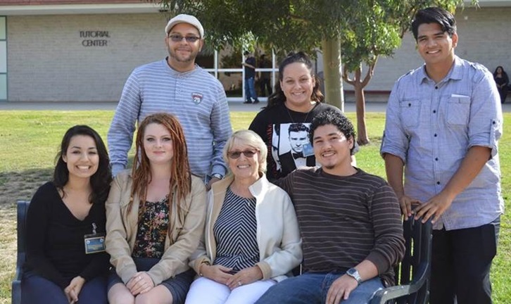 four people sitting and three people standing looking at camera and smiling