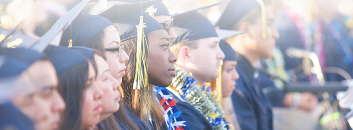 students standing at a graduation ceremony, wearing caps and gowns