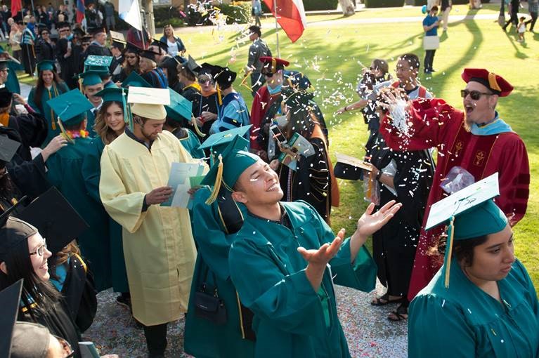 photo of graduating students in caps and gowns at an outdoor ceremony