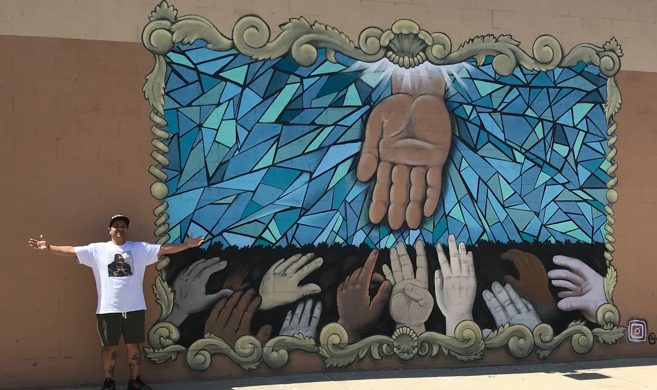 This image shows Clovis Community College student Arturo Sanchez standing in front of a mural he painted.