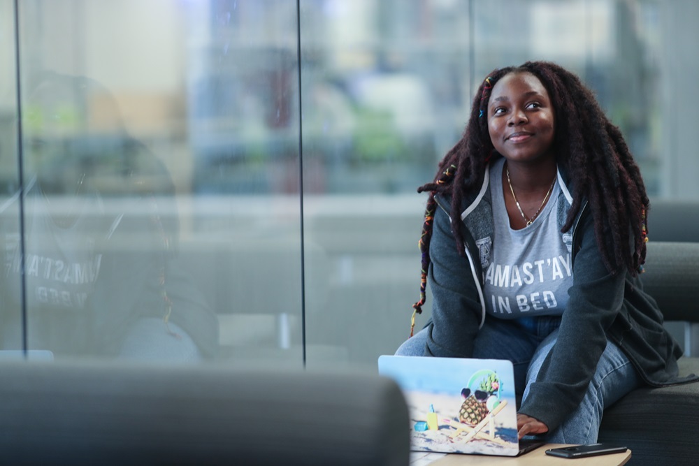 woman sitting in front of a laptop, looking up and thinking