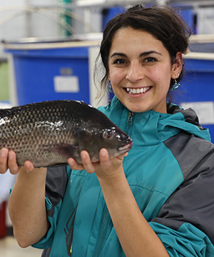 A portrait of Jasmine Iniguez holding a fish in her hands