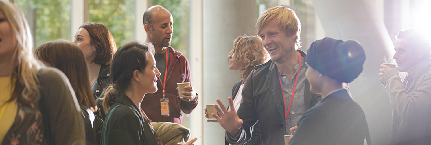 Photo of group of people standing and talking to each other at an event inside